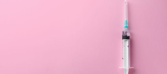 Syringe with liquid on color background